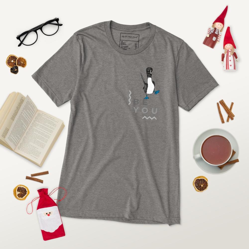 Grey triblend t-shirt featuring Be You in bold text with a detailed illustration of a blue-footed booby. Soft, lightweight fabric with a comfortable fit, showcasing lifelike textures in the artwork.