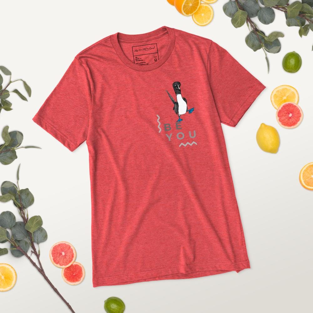 Red triblend t-shirt featuring Be You in bold text with a detailed illustration of a blue-footed booby. Soft, lightweight fabric with a comfortable fit, showcasing lifelike textures in the artwork.